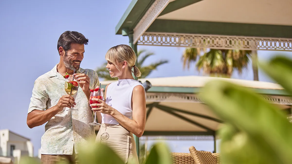 mujer sobre cama balinesa y hombre en la piscina tomando un cóctel en Welikehotel