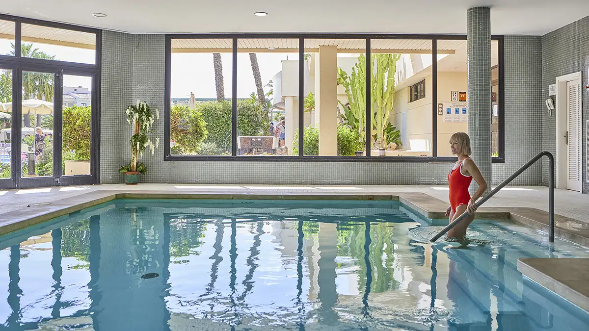 Mujer entrando en la piscina interior Welikehotel Marfil Playa