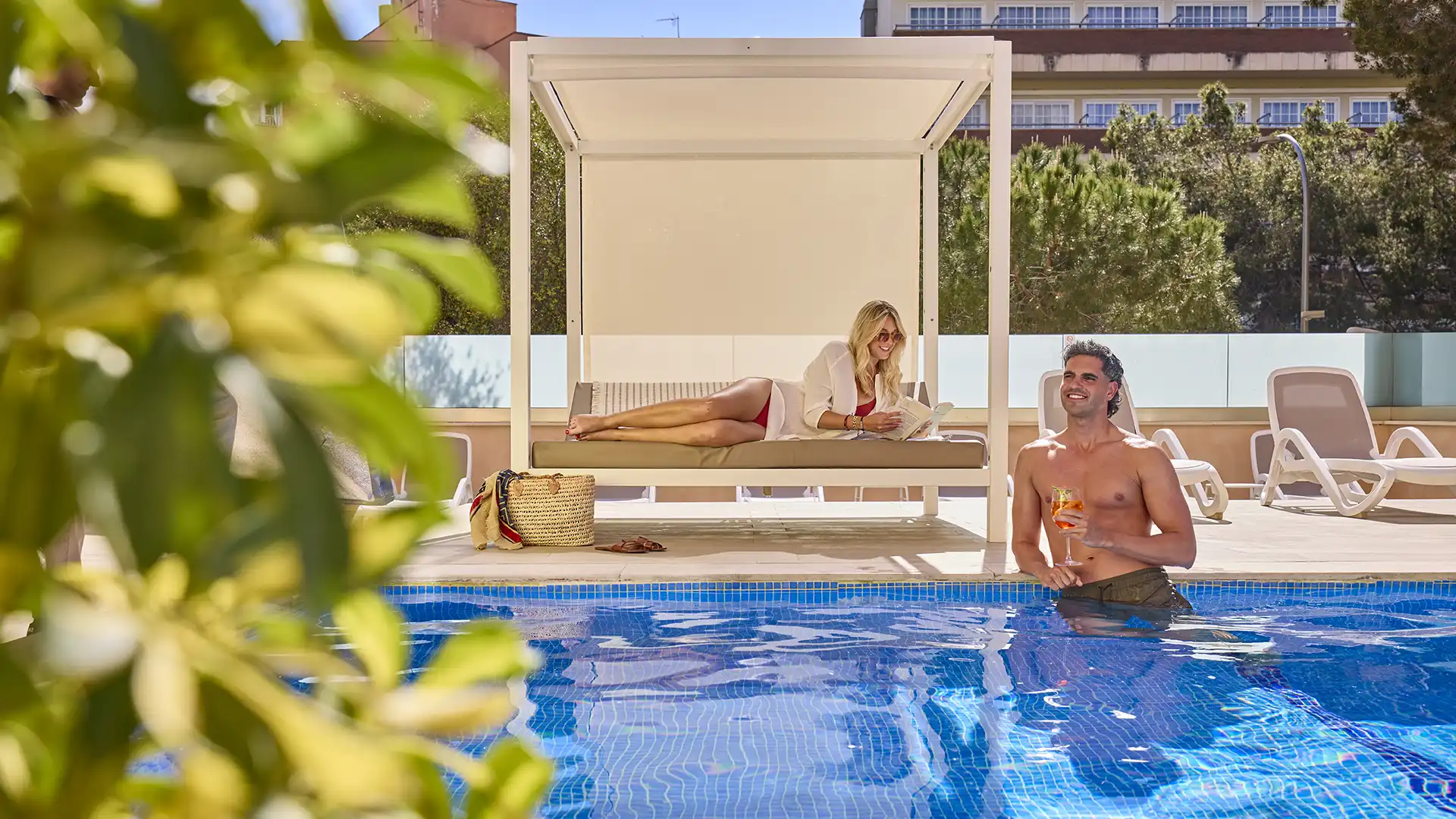 Pareja en cama balinesa y piscina del Welikehotel Fenix