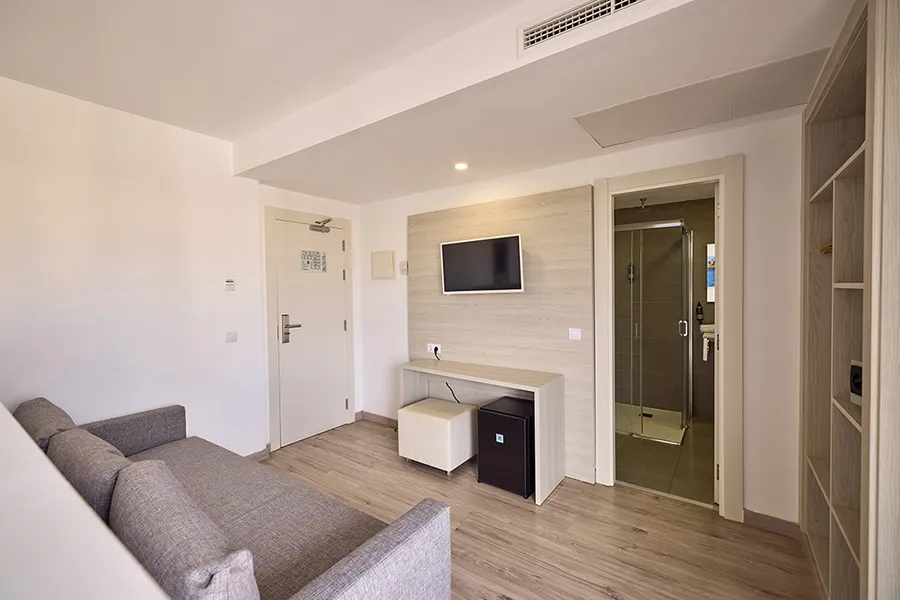 Zona de salón equipada Sofá, televisor y escritorio en zona salón de la Junior Suite con Balcón Welikehotel Fénix