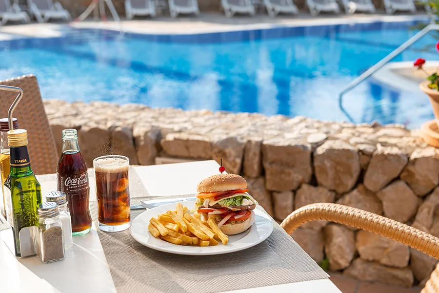 Hamburguesa Deliciosa hamburguesa con patatas en la terraza del snack-bar del hotel Welikehotel Marfil Playa