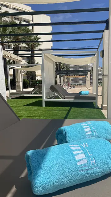 mujer sobre una cama balinesa con una copa de champagne en Welike Hotel Marfil Playa