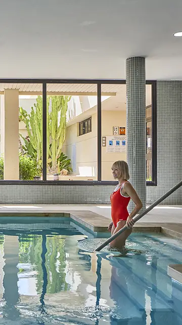 Mujer entrando en la piscina interior del Spa Welike Hote Marfil Playa