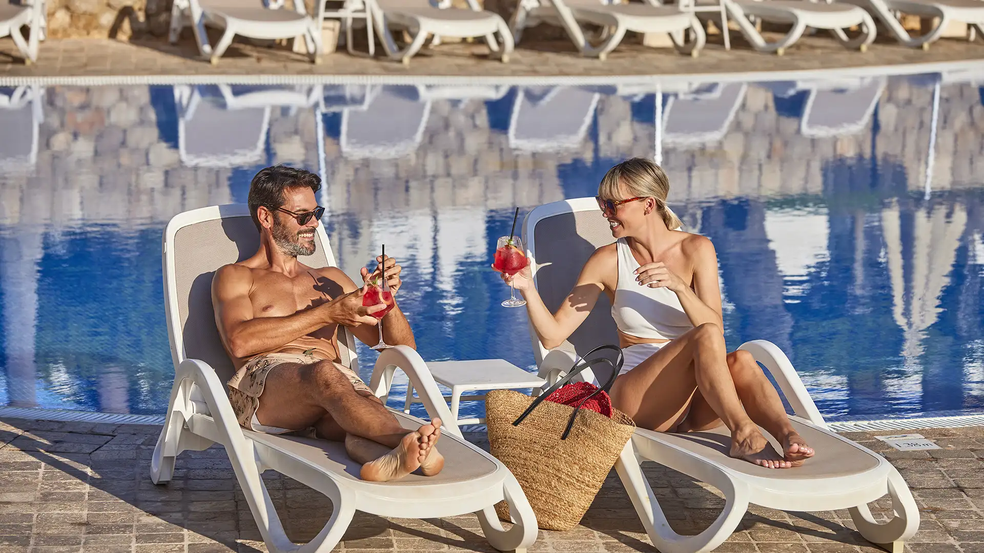 pareja en las tumbonas de la piscina tomando un cóctel welikehotel Marfil Playa